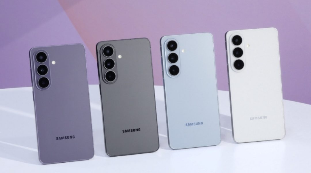 Four Samsung Galaxy phones in purple, gray, blue, and white stand upright on a white surface with triple-camera backs visible (brand logo at bottom).